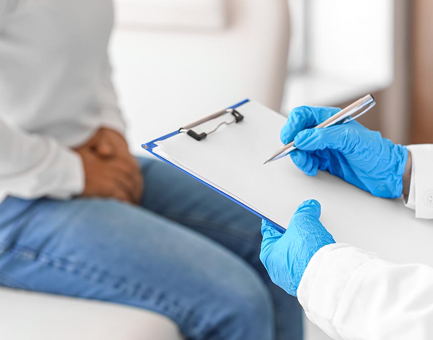 Médico frente a paciente sosteniendo tabla de cuestionario, paciente sentado frente a médico.