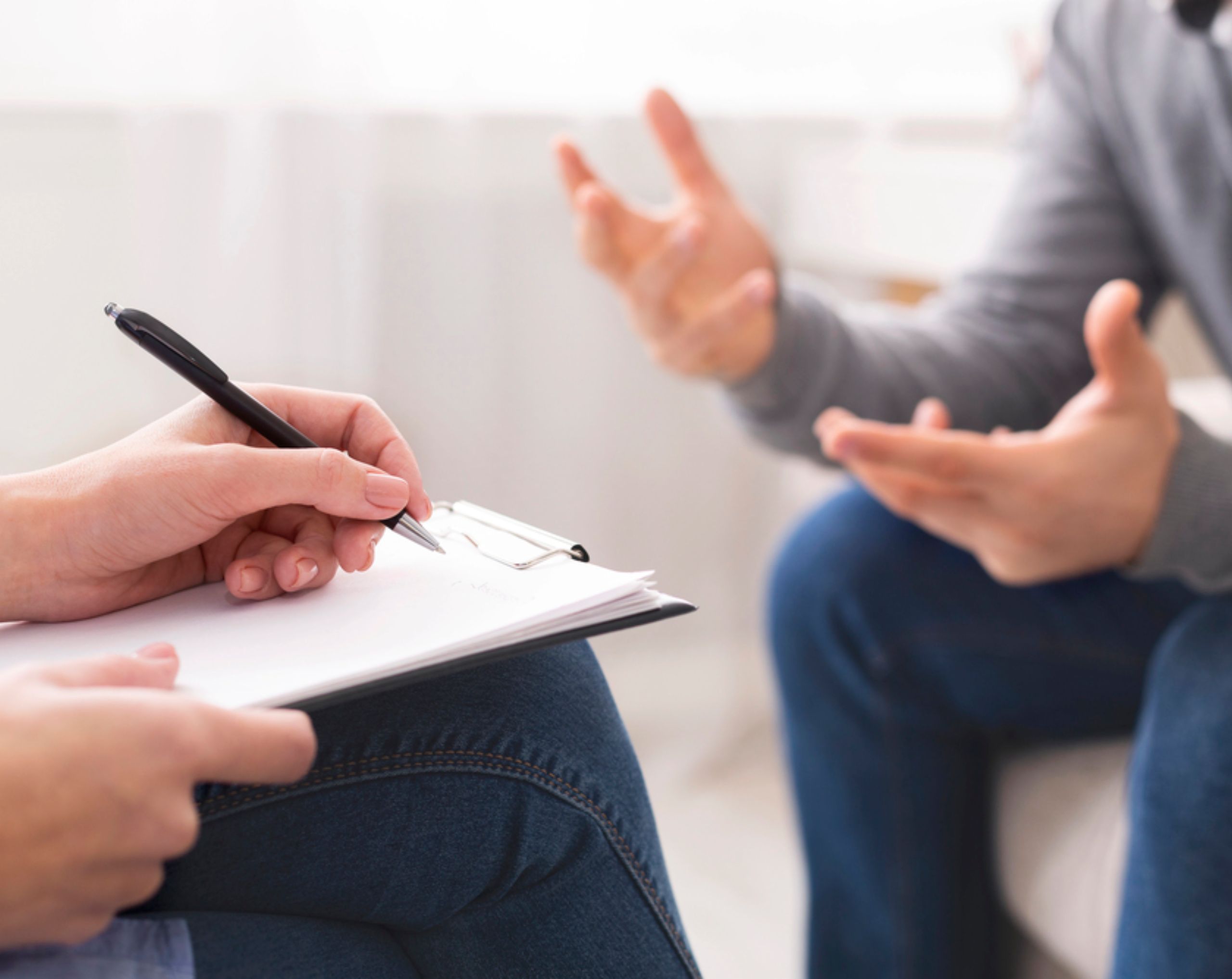 Paciente masculino sentado en un sofá frente a un profesional de la salud durante una sesión de psicoterapia, tratamiento utilizado para la esquizofrenia.