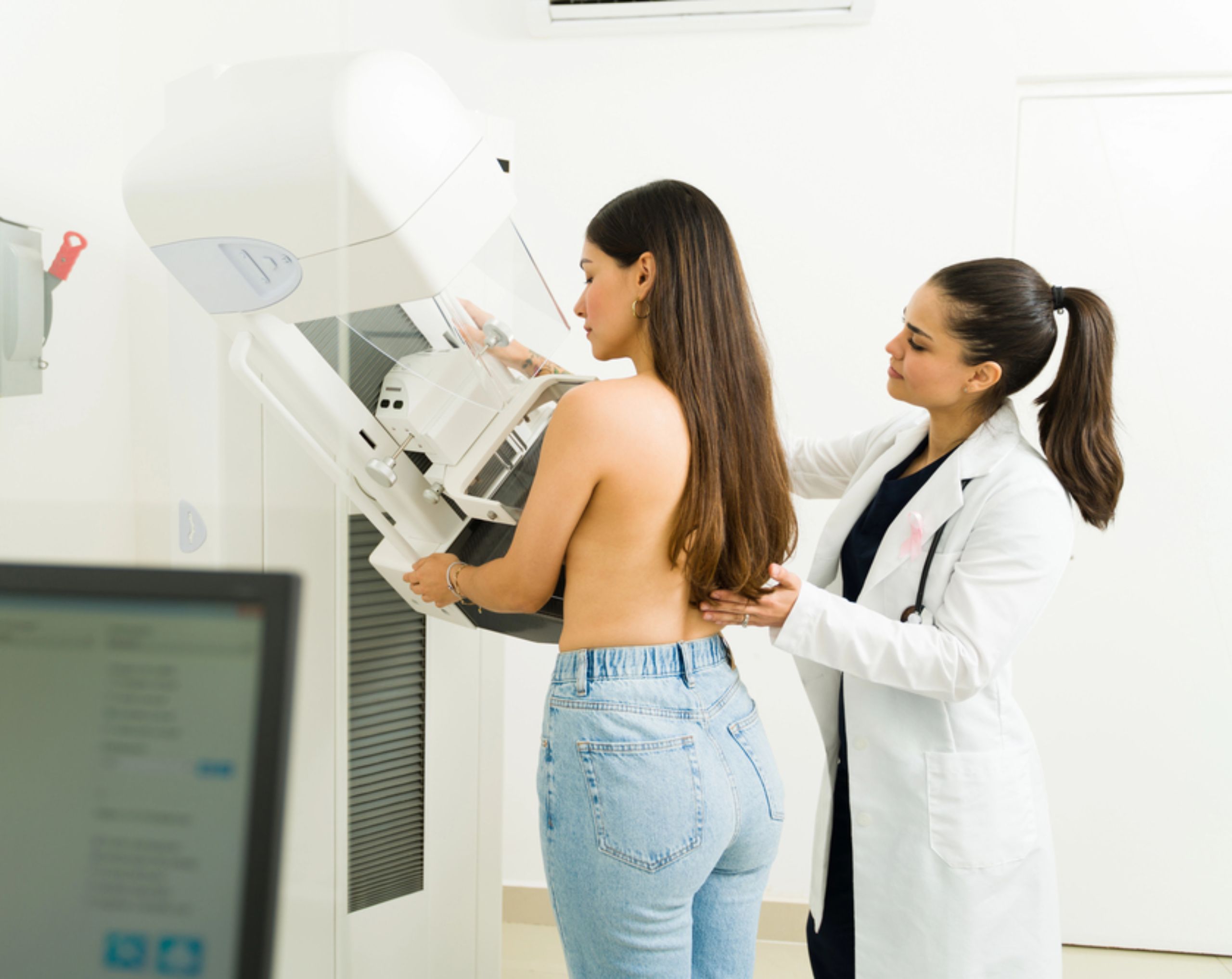Médica realizando prueba de detección a mujer joven para prevenir el cáncer de mama. 