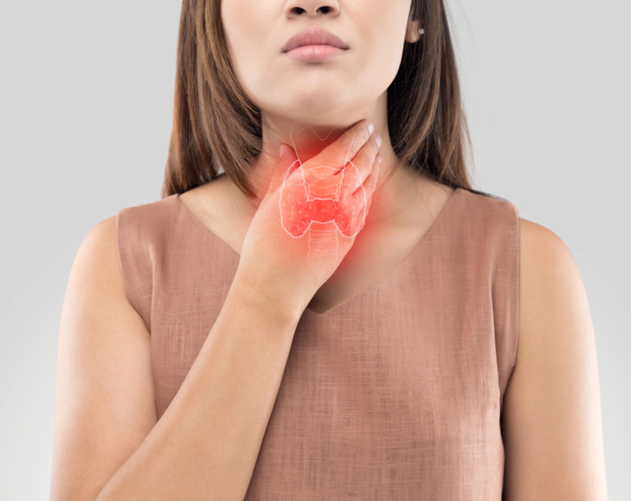 Mujer joven sostiene su cuello con una mano y muestra una expresión de dolor, como posible síntoma de cáncer de tiroides en adultos jóvenes.
