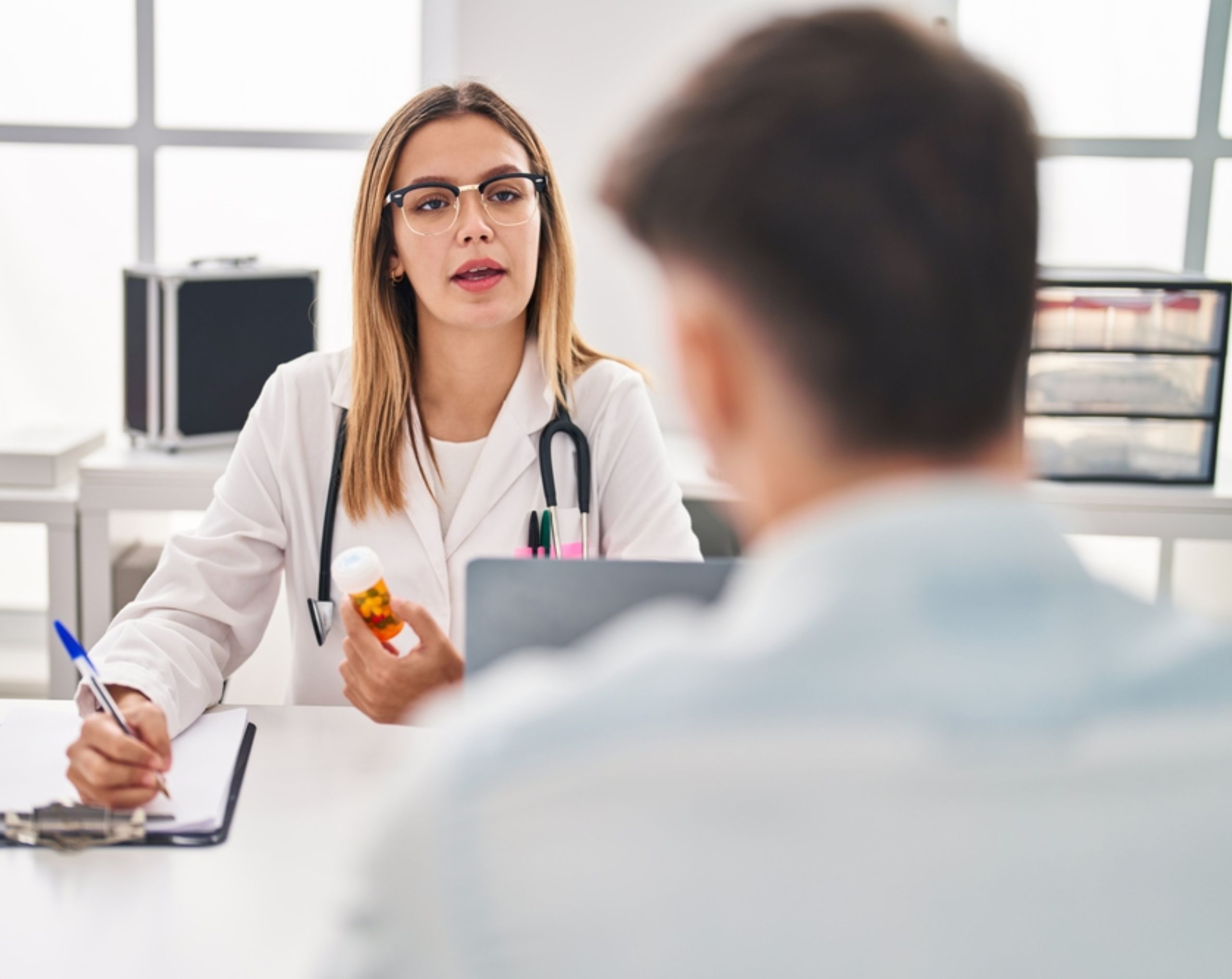 Hombre joven sentado frente a una médica durante una consulta para el diagnóstico de cáncer en adultos jóvenes.