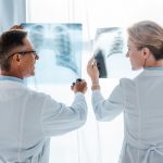 Dos médicos observan a contra luz dos radiografías de tórax producidas con rayos x.