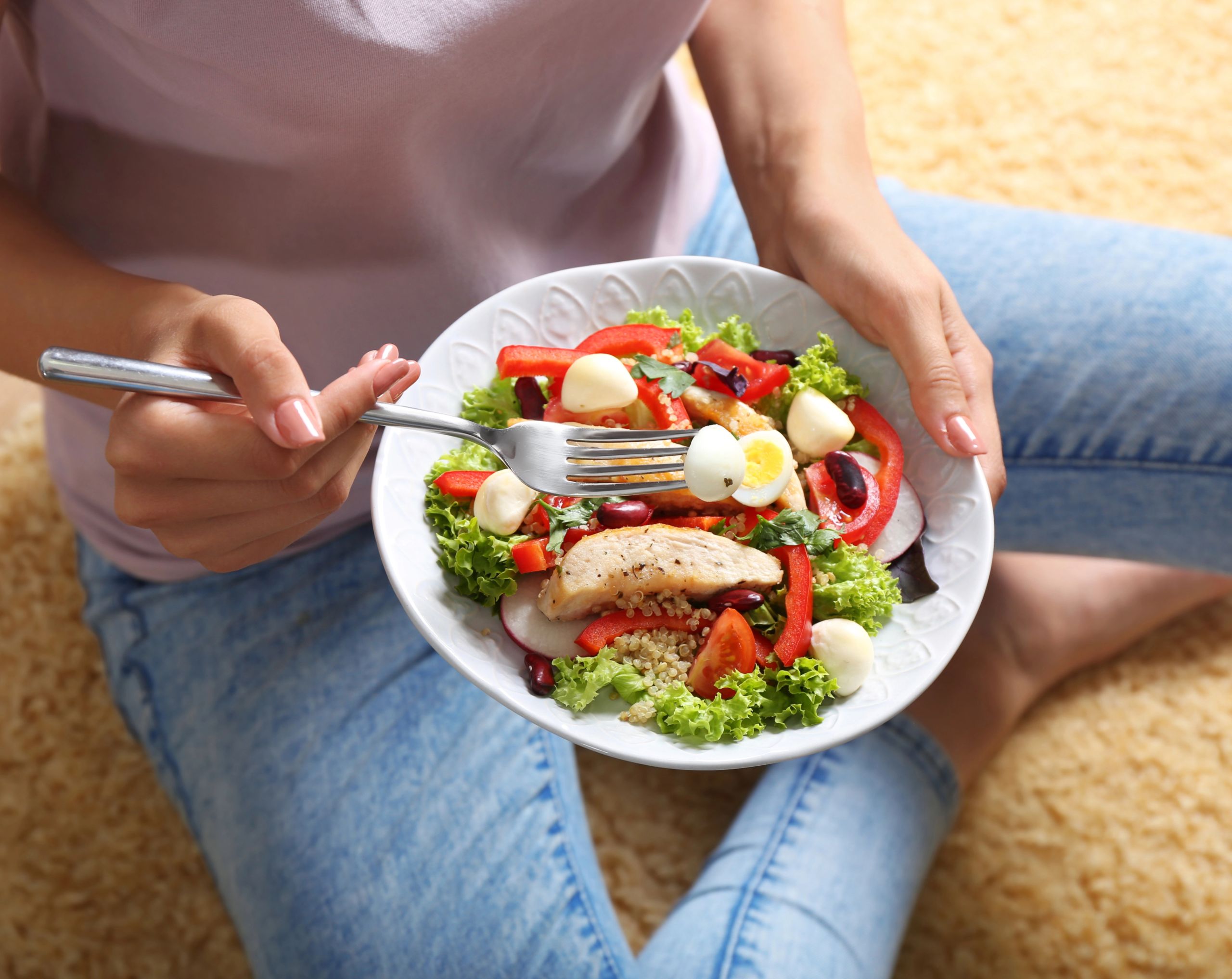 Mujer joven sosteniendo un plato con comida de dieta keto, rica en grasas saludables y baja en carbohidratos.
