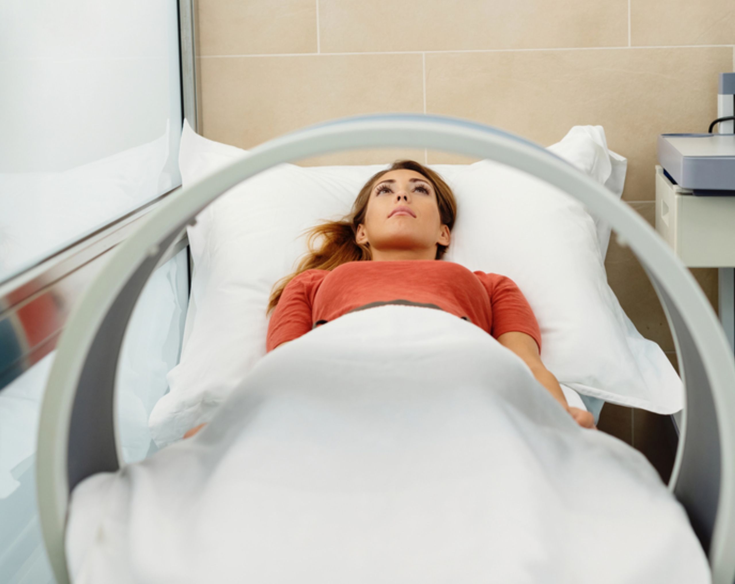 Mujer joven recostada en una camilla junto a un dispositivo de magnetoterapia, recibiendo tratamiento terapéutico para aliviar dolor o inflamación.