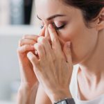 Mujer joven se toca los senos paranasales debido a molestias causadas por la sinusitis.