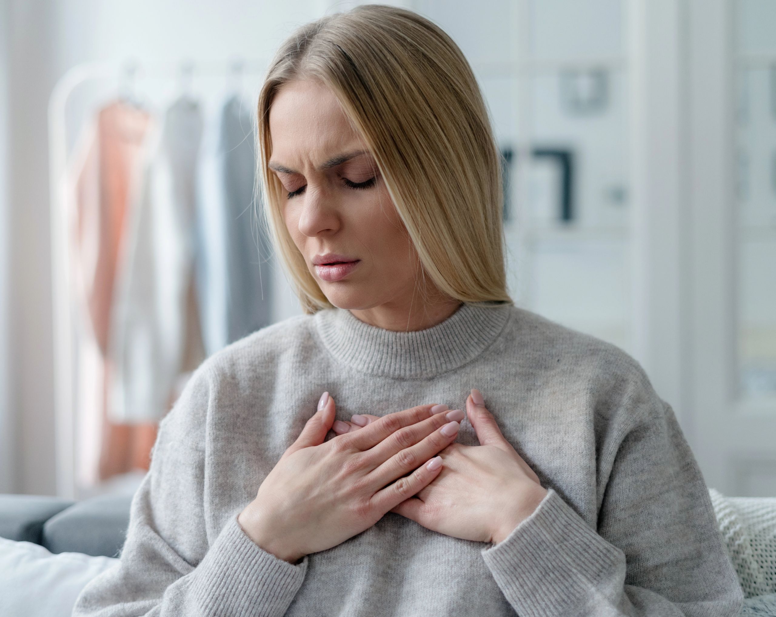 Mujer de mediana edad toca su pecho a la altura del corazón por dolor, síntoma asociado a la miocardiopatía dilatada.