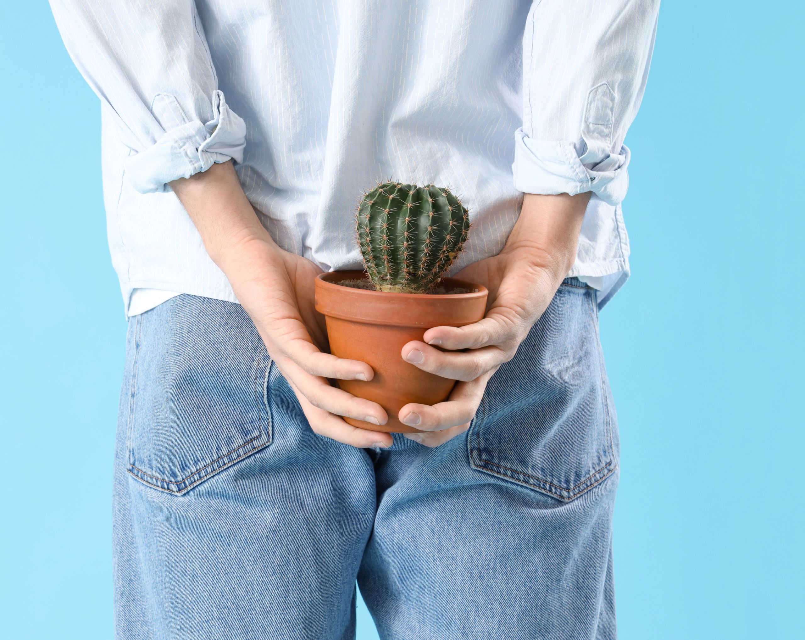 Mujer de espaldas sosteniendo un cactus con ambas manos, simbolizando la picazón anal causada por hemorroides internas.