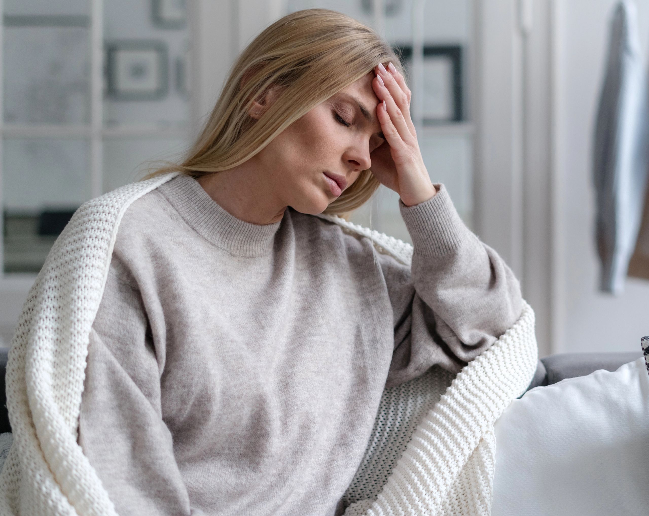 Mujer joven sentada en un sillón debido a mareos, síntoma común de disautonomía.