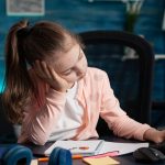 Niña pequeña sentada frente a una computadora con expresión distraída, mostrando dificultad para concentrarse, posible síntoma de TDAH.