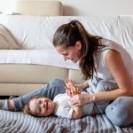 Madre jugando en un tapete con su hijo pequeño con trisomía 21 o síndrome de Down.