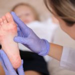 Médico infectólogo pediátrico revisando el pie de un paciente infantil que ha contraido la enfermedad mano pie boca.