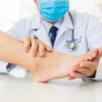 Médico dermatólogo revisando los pies de un paciente que sufre de hongos en las uñas.