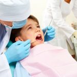 Niño pequeño en consultorio dental revisado por un odontopediatra durante la dentición.