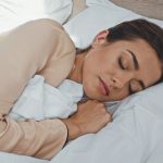 Mujer adulta durmiendo profundamente en su cama tras tomar un suplemento de melatonina para conciliar el sueño.