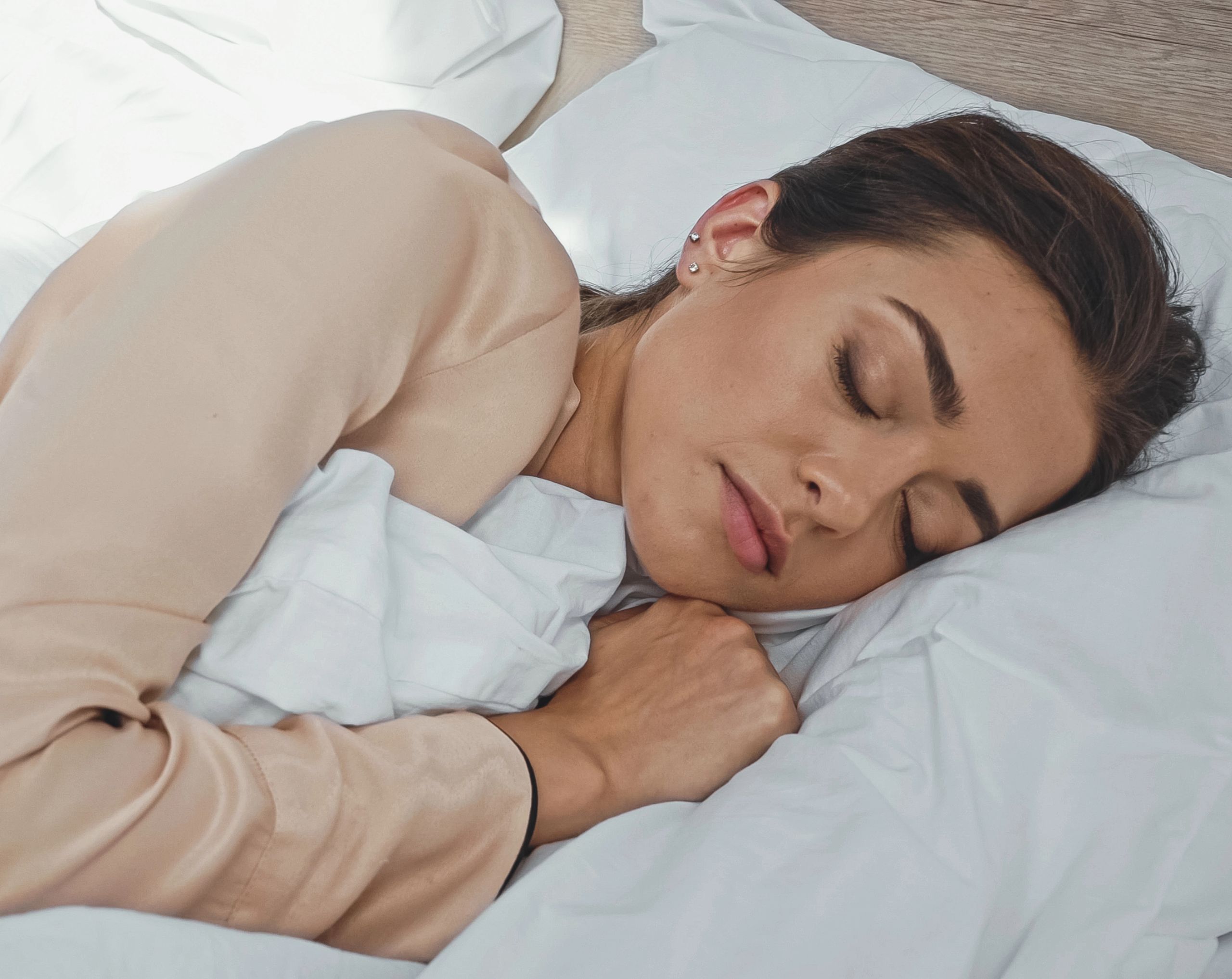 Mujer adulta durmiendo profundamente en su cama tras tomar un suplemento de melatonina para conciliar el sueño.