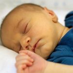 Bebé recién nacido duerme de perfil y su piel muestra la coloración amarilla propia de la ictericia.