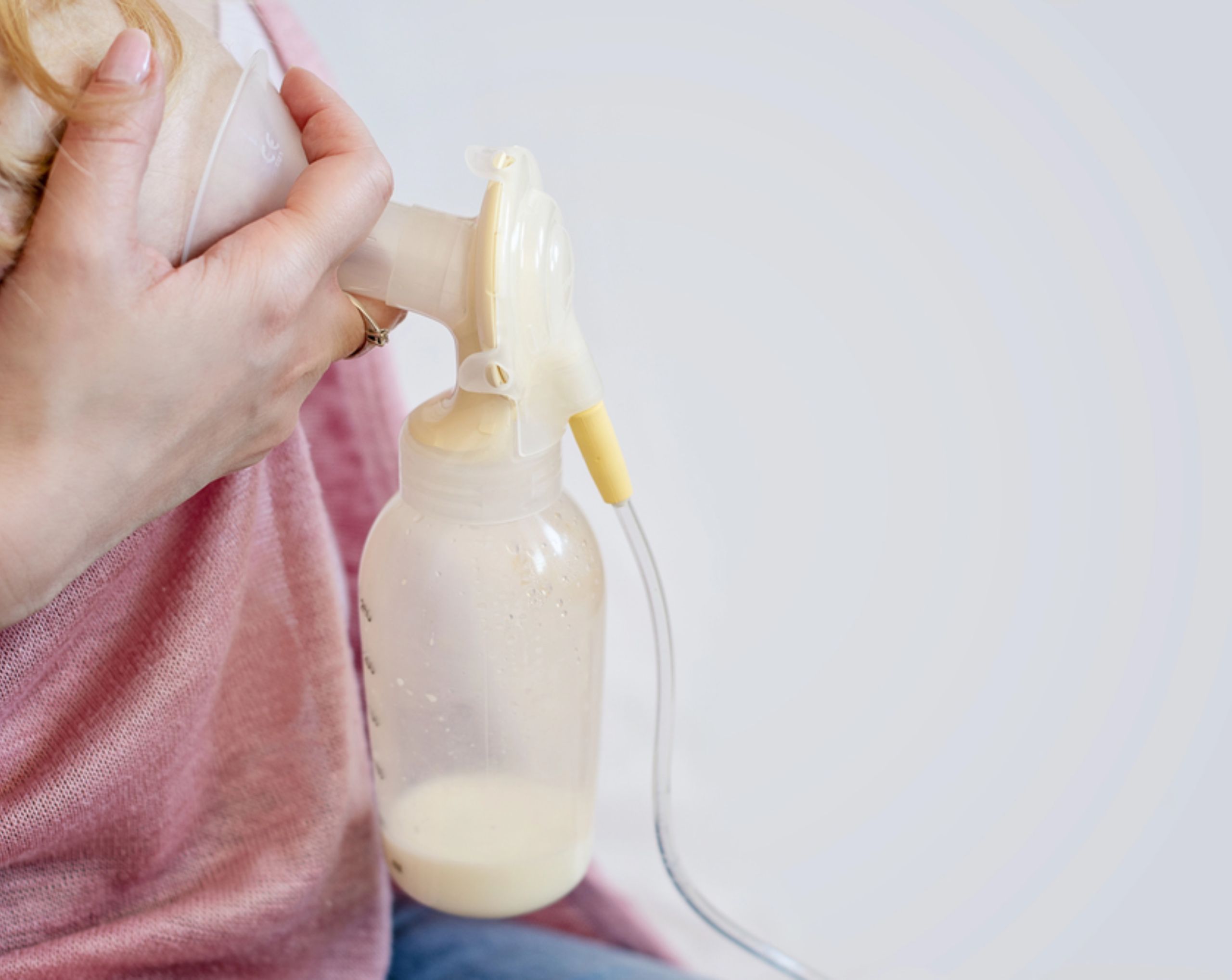 Mujer de mediana edad sostiene un extractor de leche materna para ilustrar la salida de leche por el pezón asociada con la galactorrea.