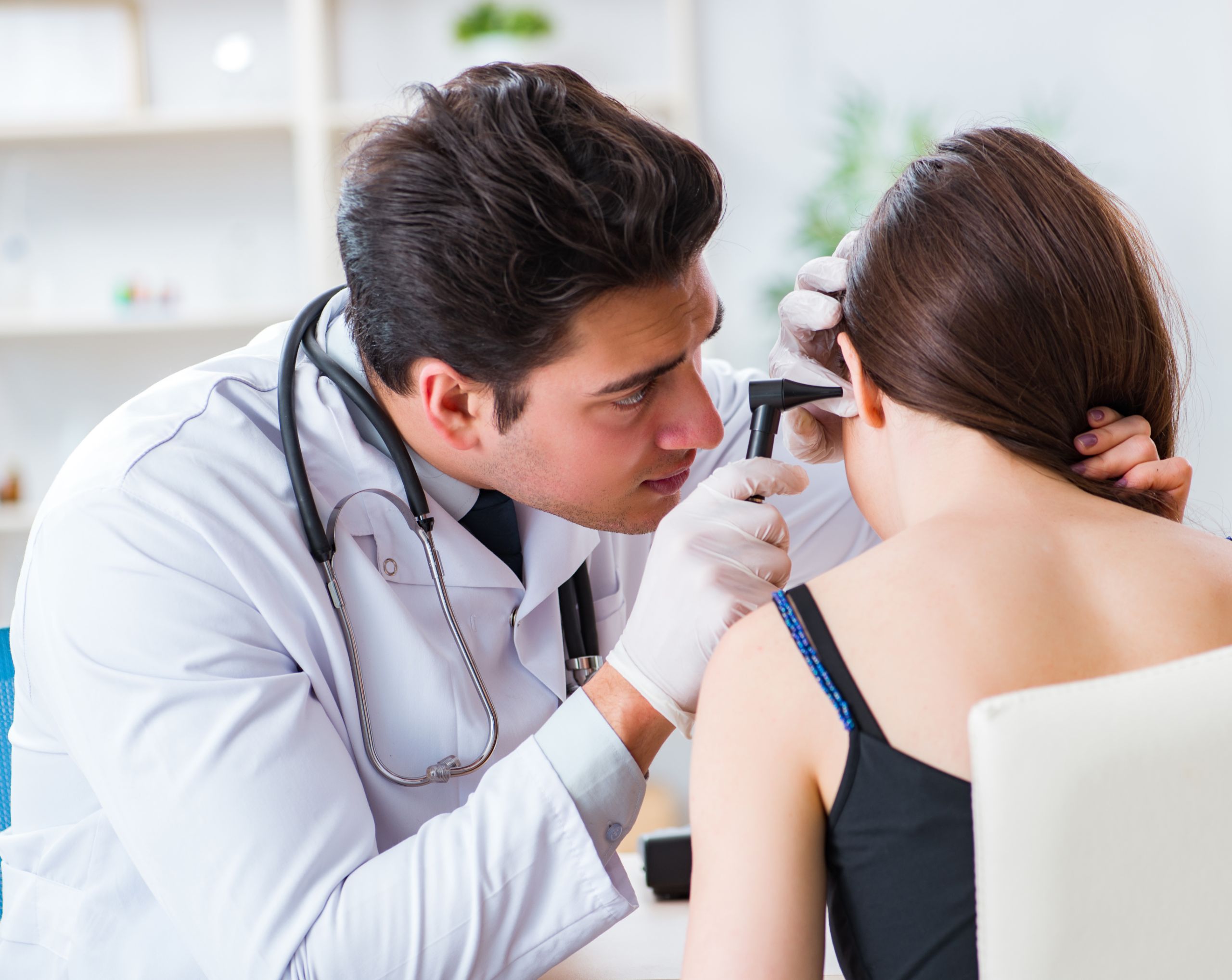 Otorrinolaringólogo examina a una paciente mujer para descartar o confirmar la necesidad de una timpanoplastia.