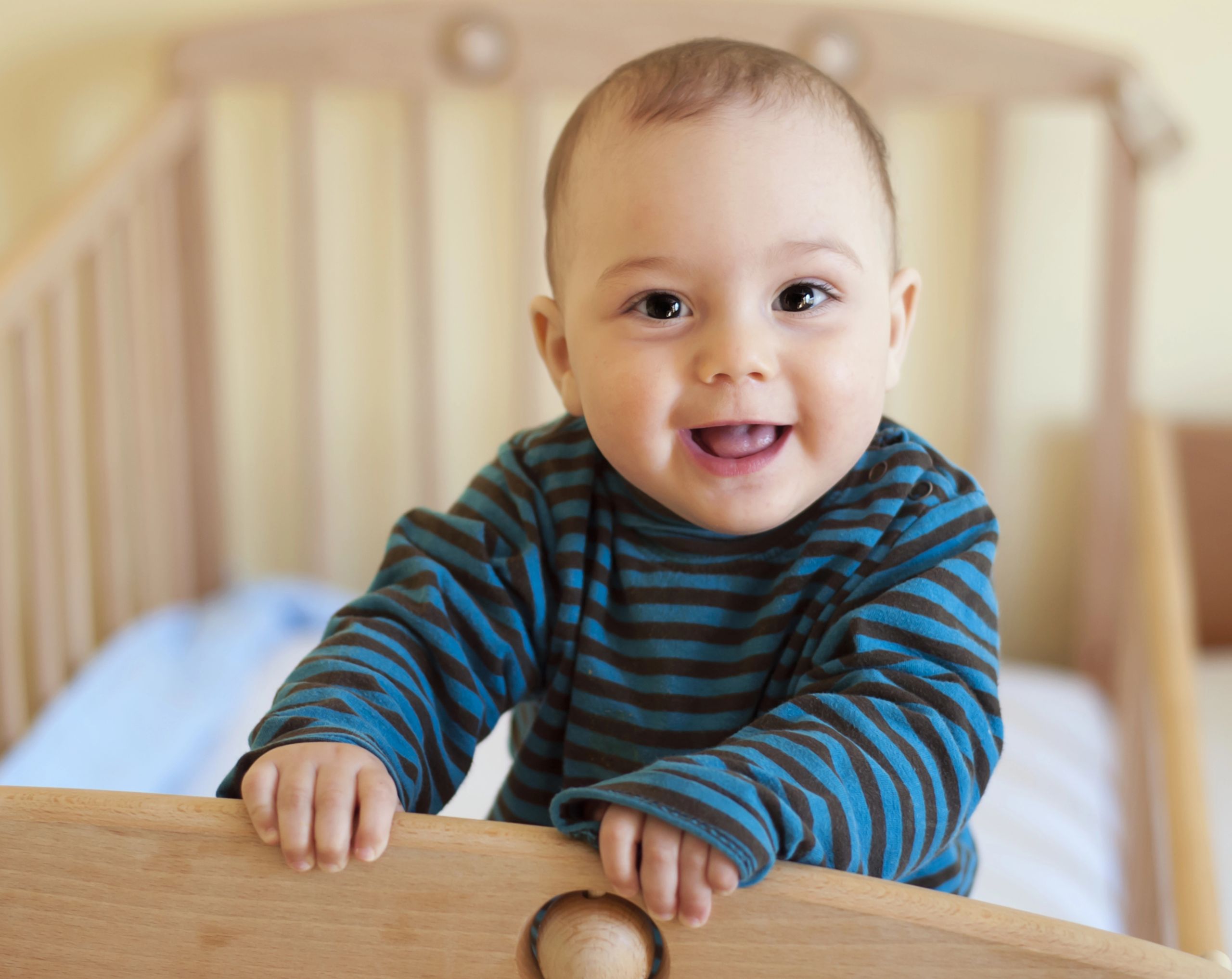 Bebé dentro de su cuna mostrando la lengua con parches blancos característicos del algodoncillo en bebés.