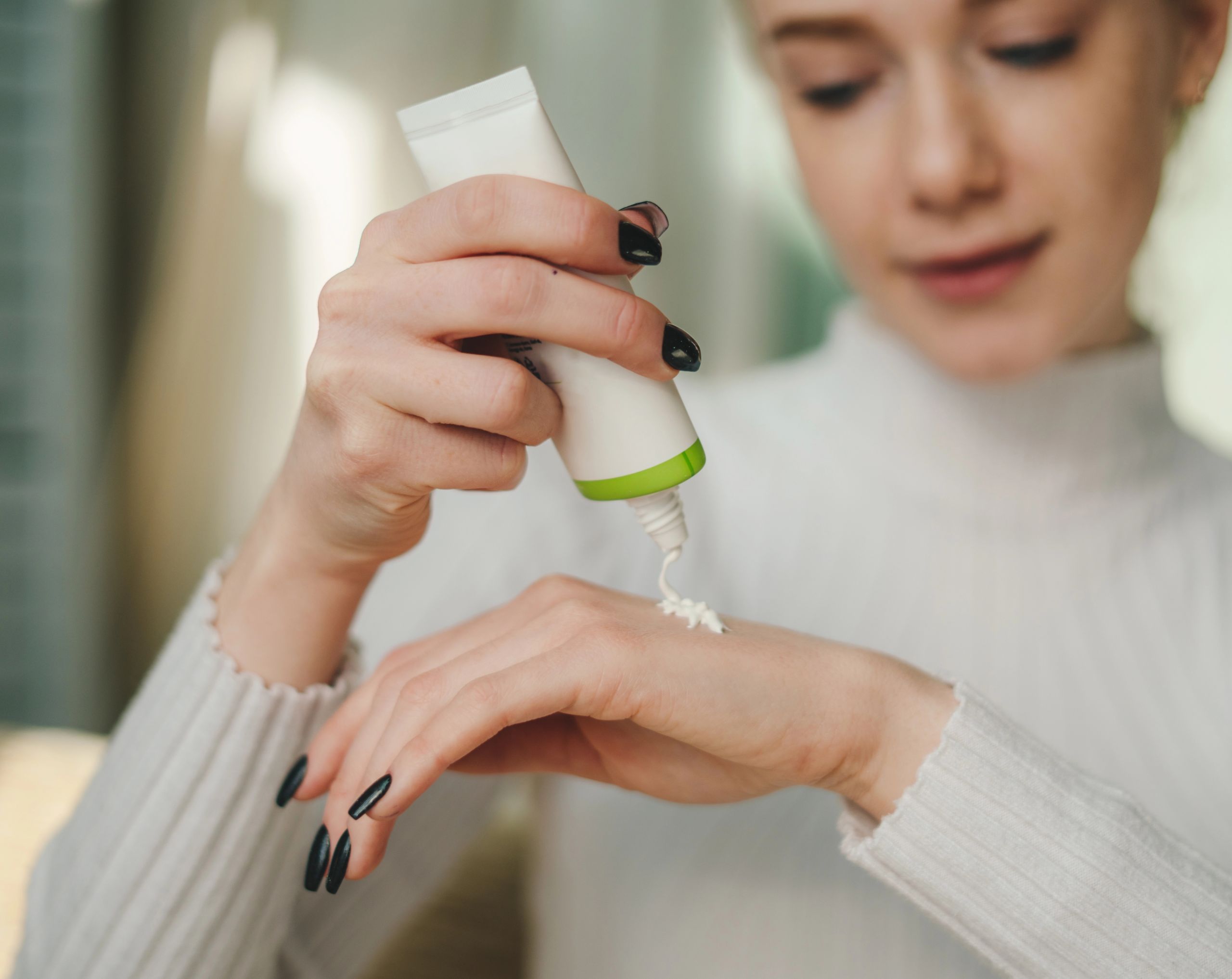 Mujer joven aplicando crema en la mano como parte del tratamiento para la dishidrosis.
