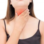 Mujer joven con la mano en la laringe, representación de síntomas asociados al cáncer de laringe.