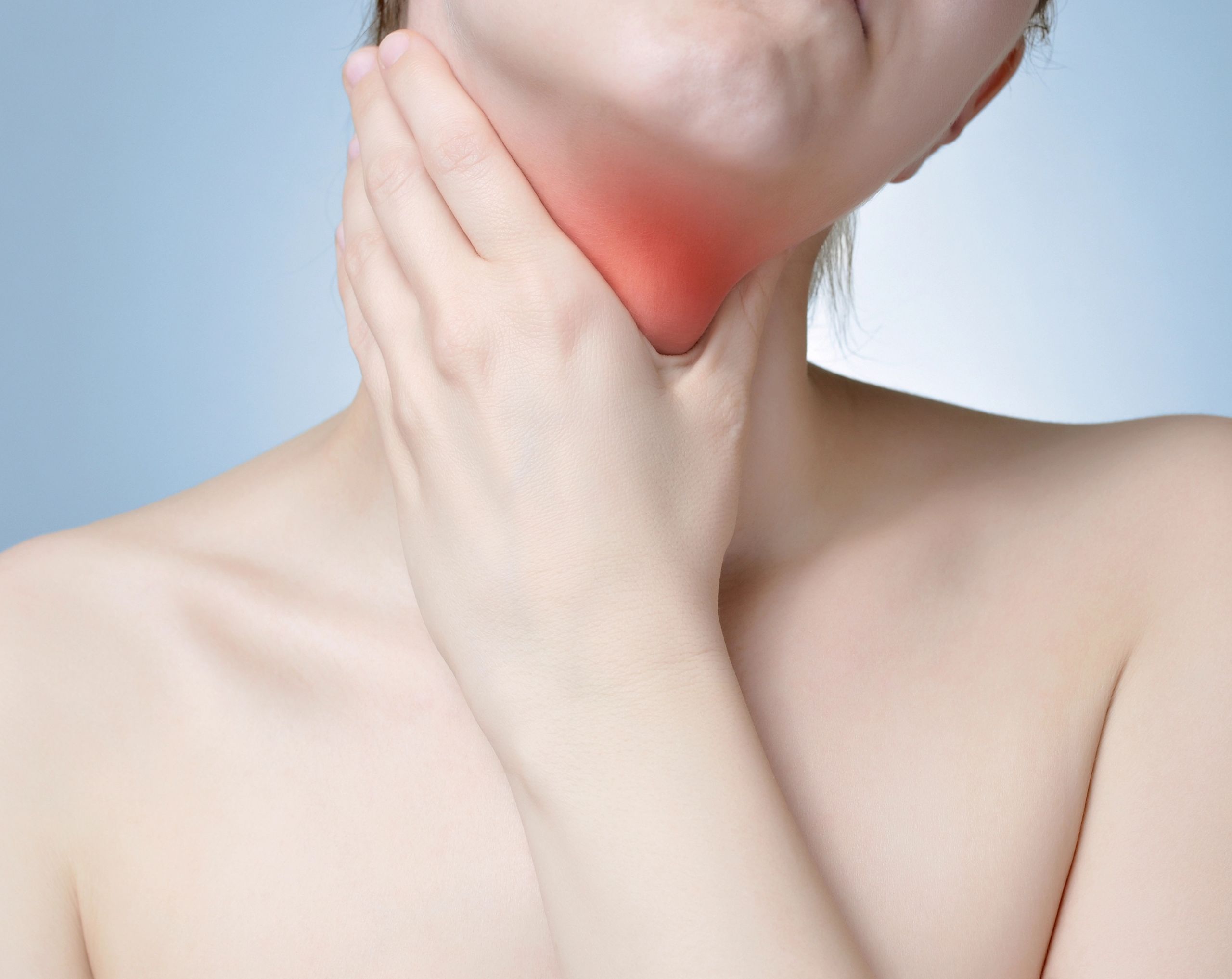 Mujer joven sostiene el cuello por dolor o molestia en la laringe, relacionado con cáncer de laringe.