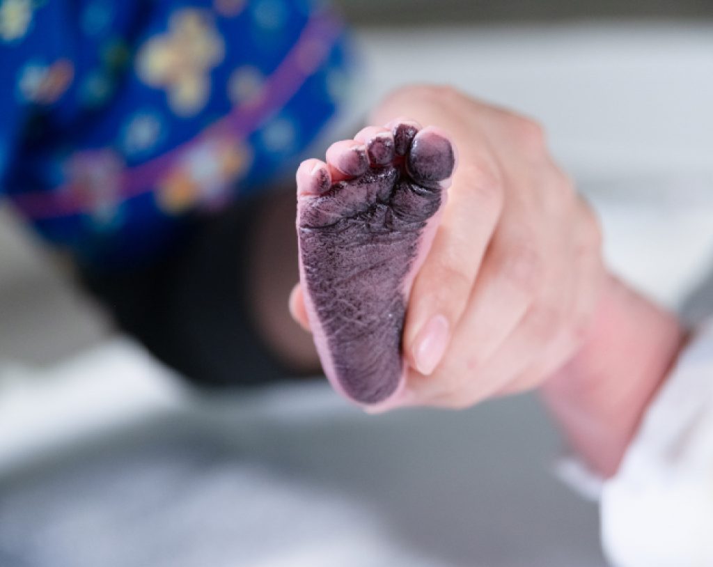 Fotografía close-up del pie de un recién nacido lleno de tinta debido a que le han tomado huellas en los cuneros de Hospital Angeles Morelia.