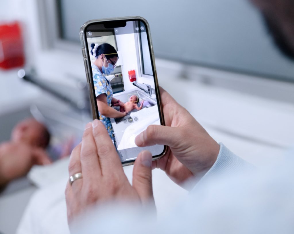 Padre de familia toma fotografía de su recién nacido siendo atendido por una enfermera experta en los cuneros de Hospital Angeles Morelia.