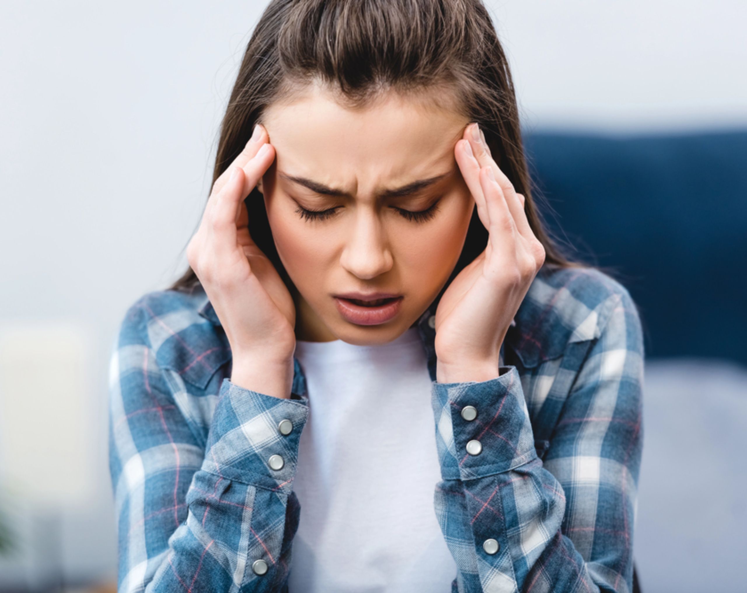 Mujer tocando sus sienes por dolor de cabeza, uno de los síntomas del dengue.