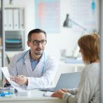 Doctor en su consultorio con una paciente, mostrándole la nueva alianza de Hospital Angeles con la aseguradora Axa.
