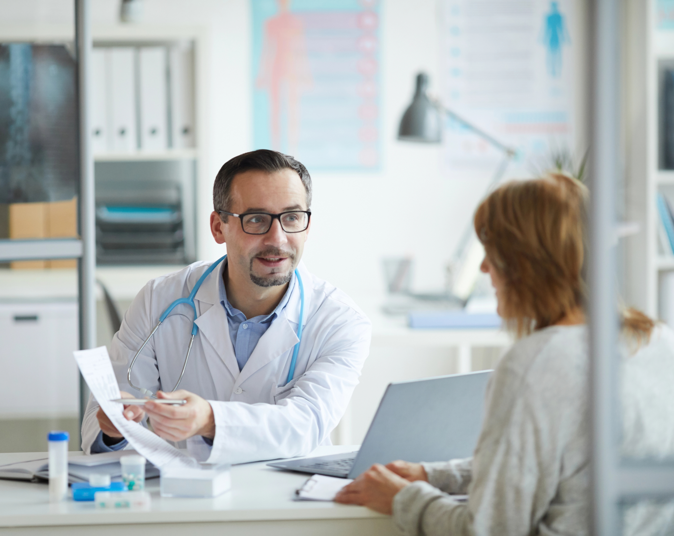 Doctor en su consultorio con una paciente, mostrándole la nueva alianza de Hospital Angeles con la aseguradora Axa.
