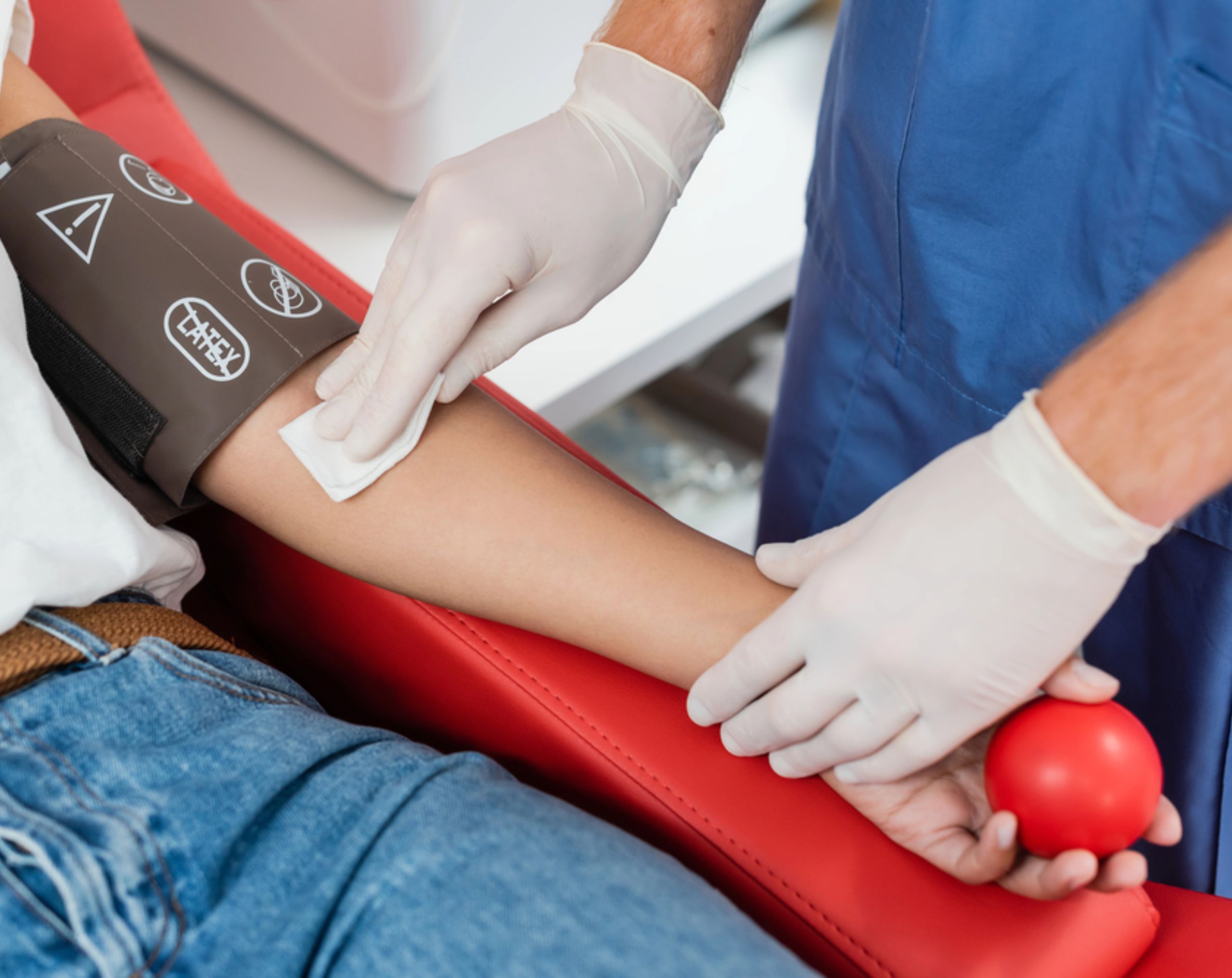 Enfermero coloca algodón en el brazo de un donador altruista después de una donación de sangre, mientras el paciente sostiene una pelota de goma utilizada para favorecer el flujo sanguíneo durante el procedimiento.