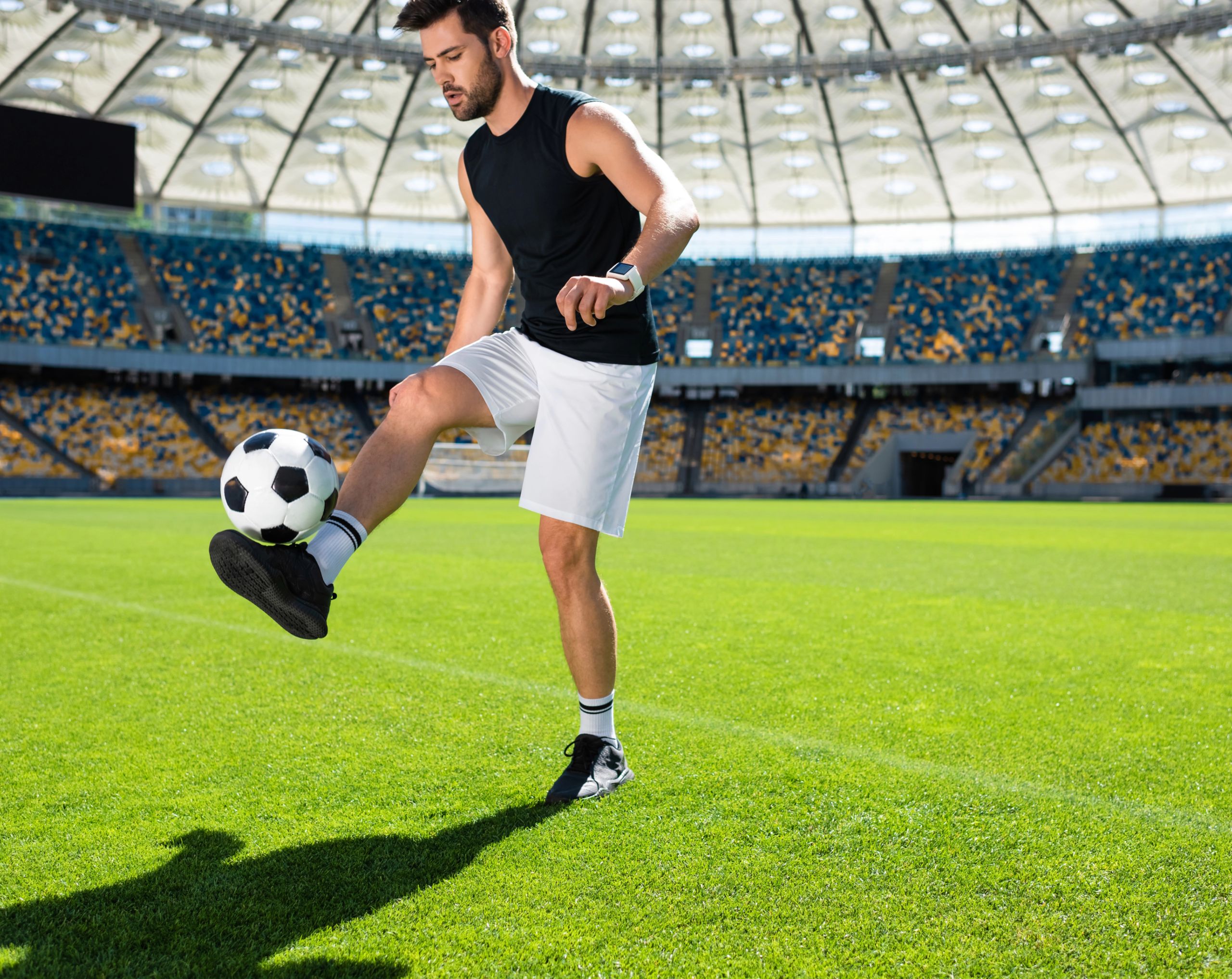 Futbolista joven entrenando en cancha con balón, durante partifo de futbol,  actividad física asociada al rendimiento y salud cardiovascular.